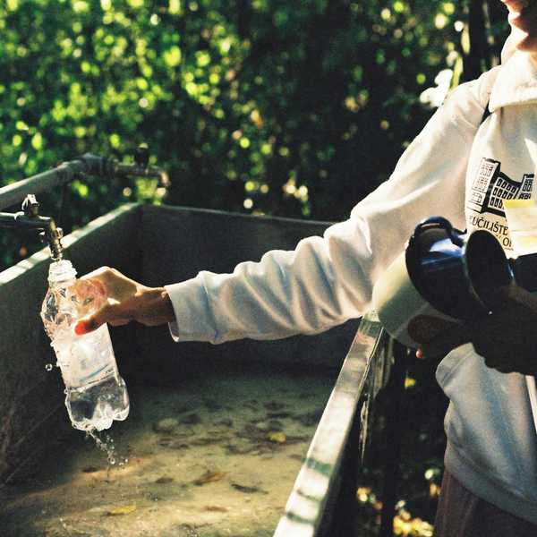 A man filling a water bottle with water holding scientific equipment.