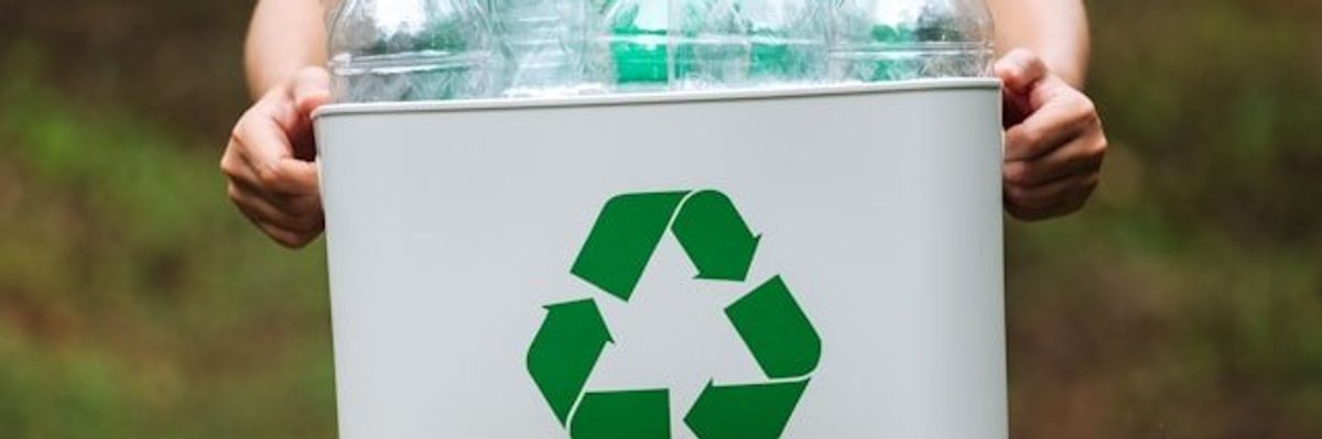 A man holding a recycling bucket filled with plastic bottles.