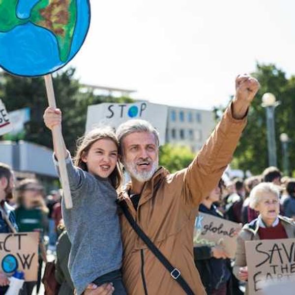 A man holding his daughter during a climate protest