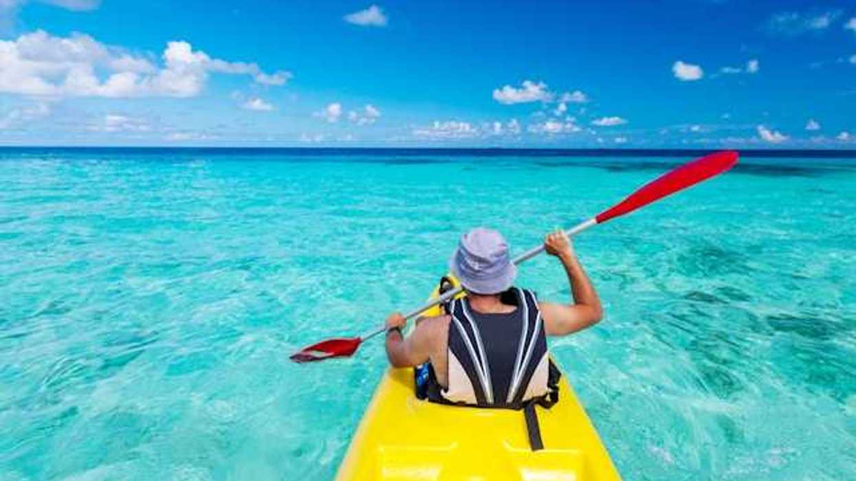 A man in a kayak paddling in turquoise waters