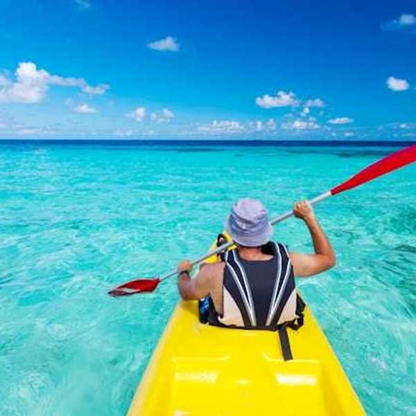 A man in a kayak paddling in turquoise waters