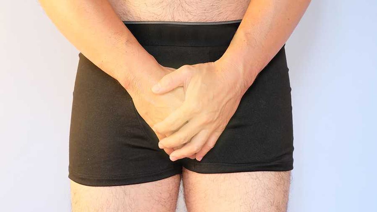 A man in briefs holding his hands over his genital area