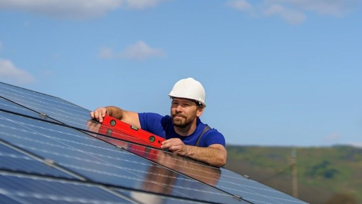 A man installing a solar panel on a roof.