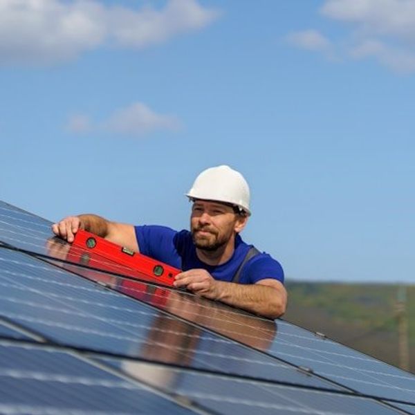A man installing a solar panel on a roof.