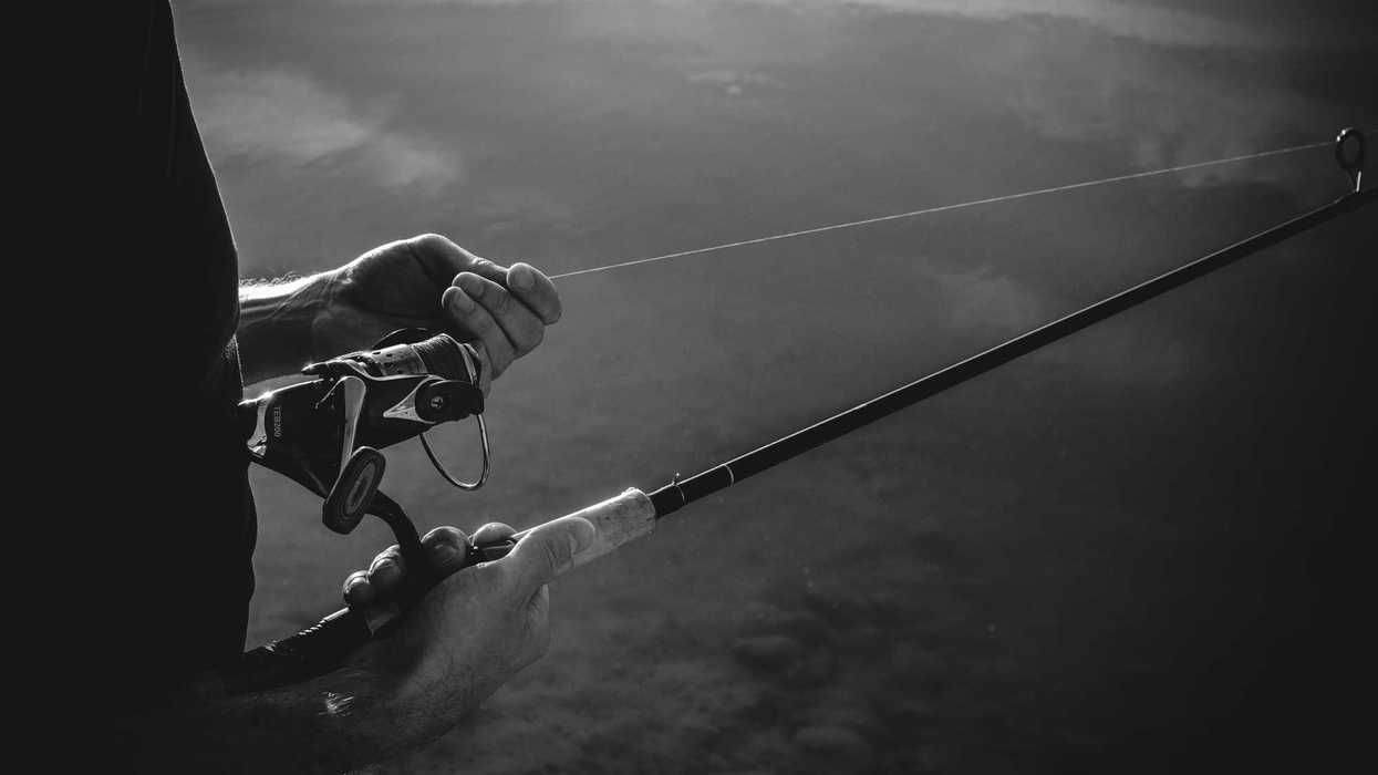 A man is holding onto fishing line in a black and white photo