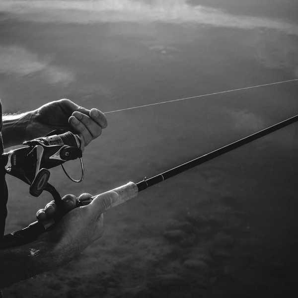 A man is holding onto fishing line in a black and white photo