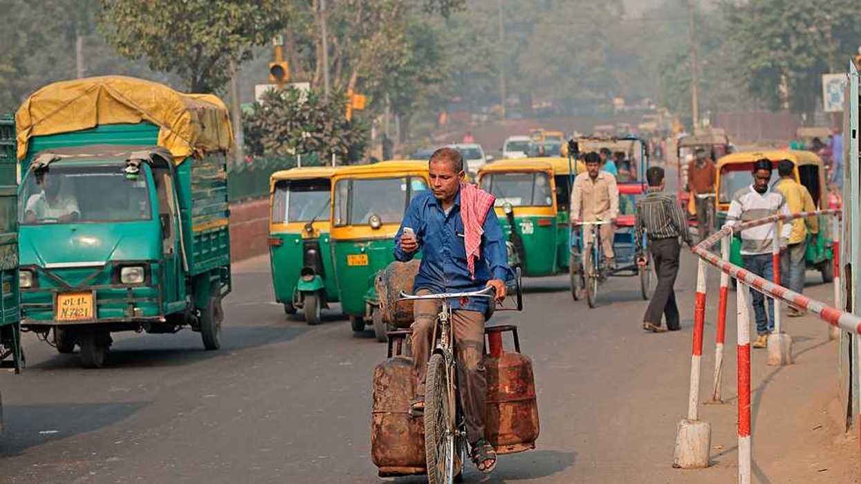 A man on a bike riding through a densely trafficked road in an Indian city