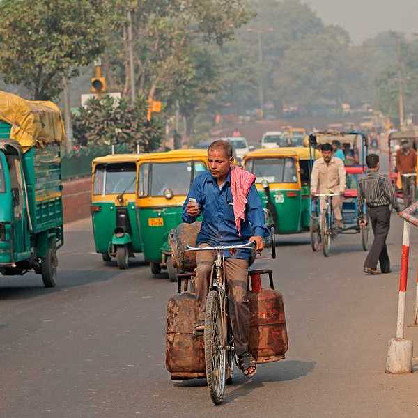 A man on a bike riding through a densely trafficked road in an Indian city