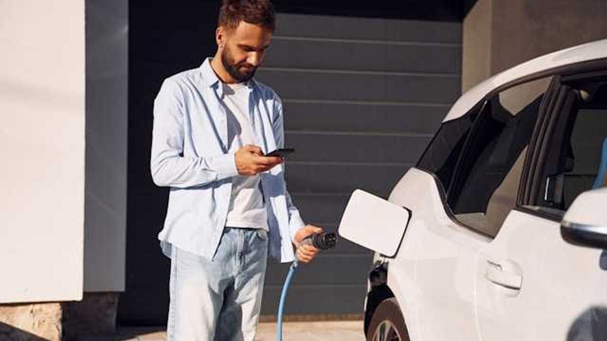 A man plugging in his electric vehicle outside his house