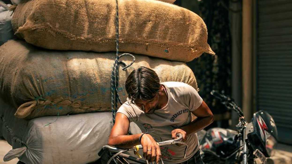 A man pulling his cycle rickshaw with a heavy boxes in Indian summers.