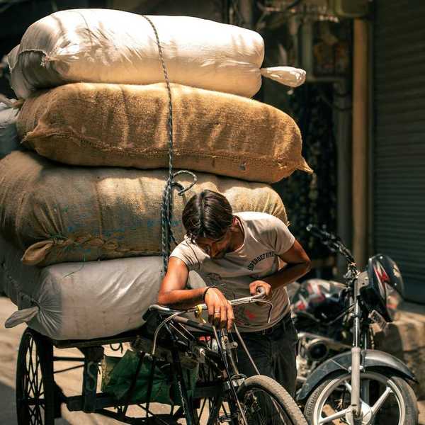 A man pulling his cycle rickshaw with a heavy boxes in Indian summers.