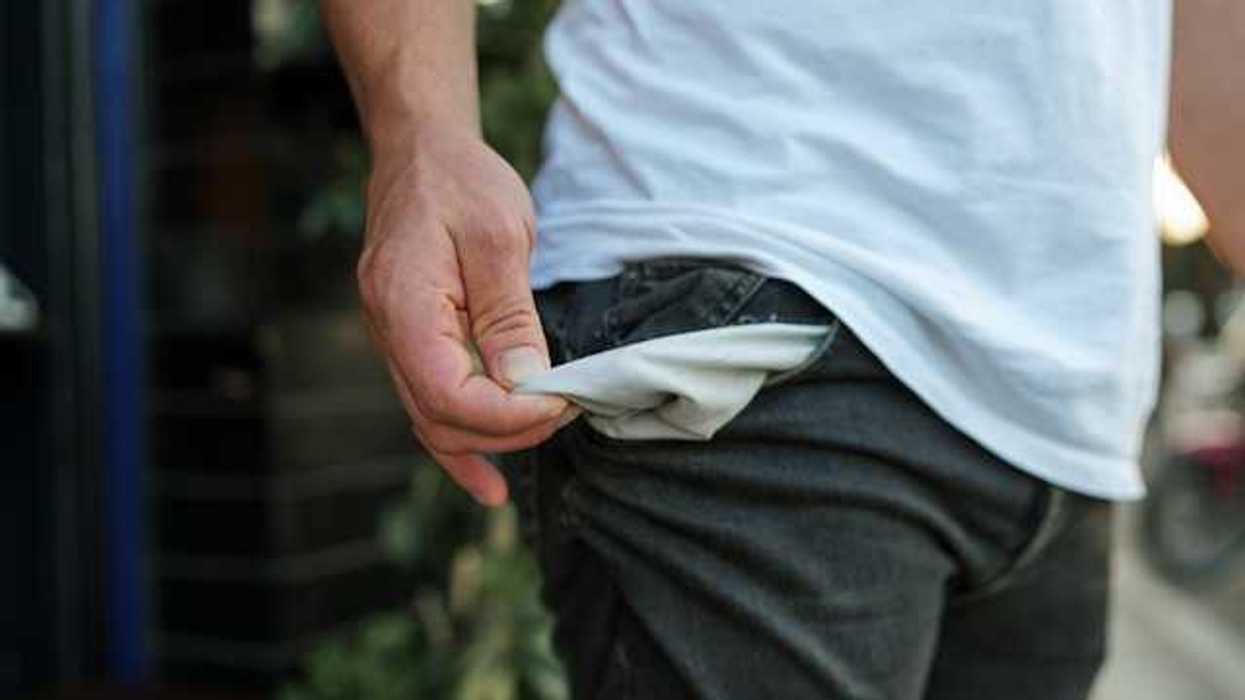 A man pulling out his pants pockets to show that they're empty