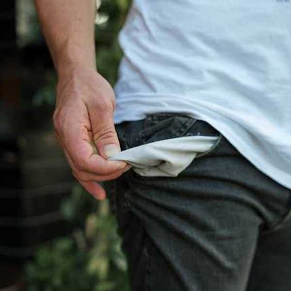 A man pulling out his pants pockets to show that they're empty