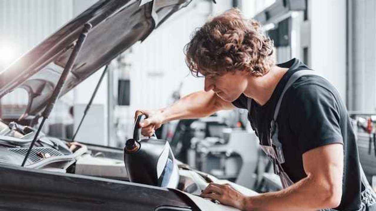 A man putting engine oil into a car