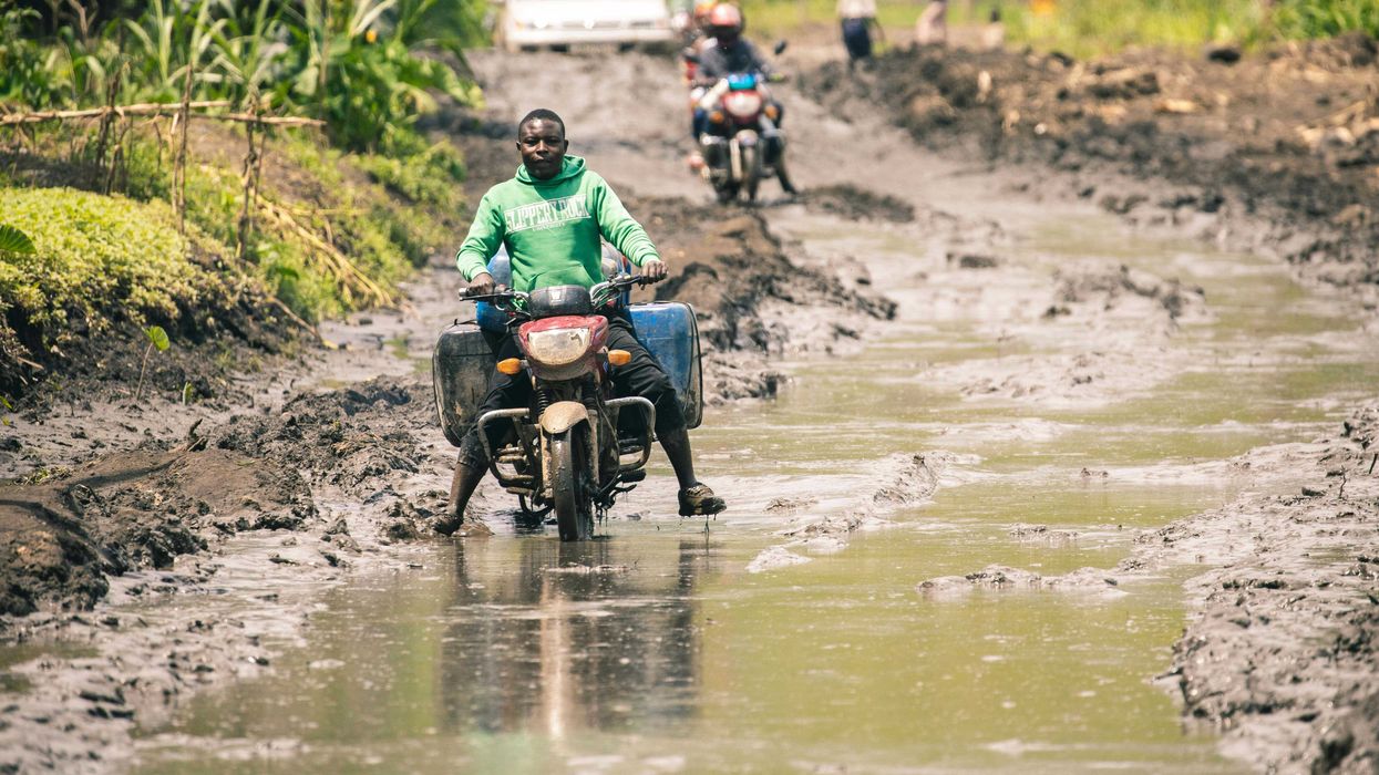A man riding a motorcycle down a muddy, flooded road.