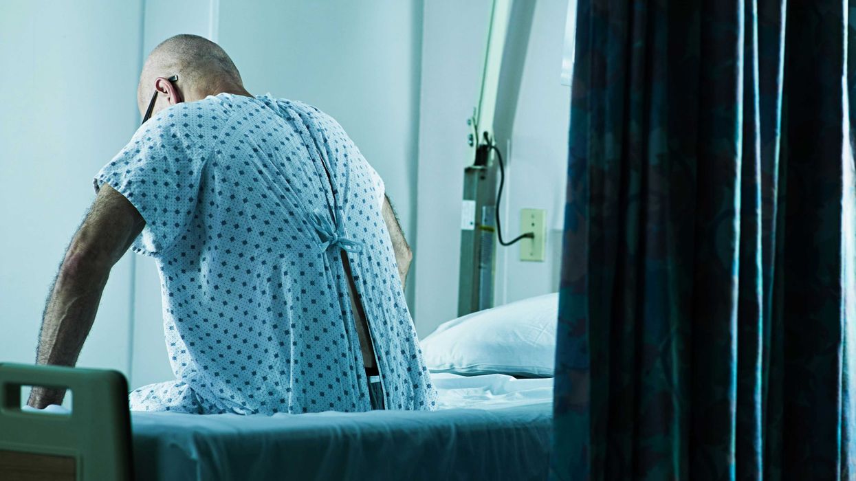 A man sits on the edge of his hospital bed