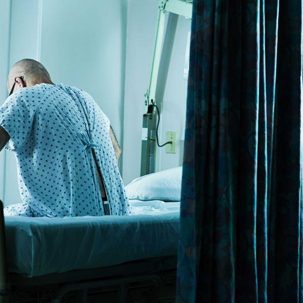 A man sits on the edge of his hospital bed