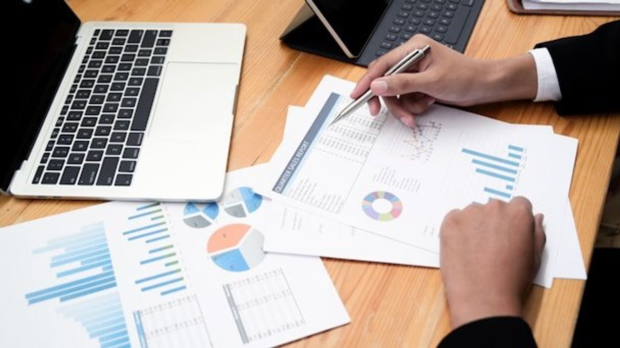 A man sitting at a desk with a laptop and computer printouts