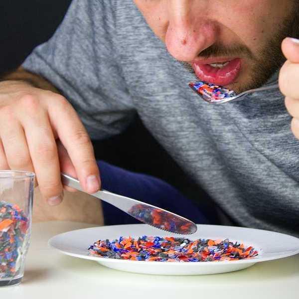A man sitting at a table eating small pieces of plastic from a plate