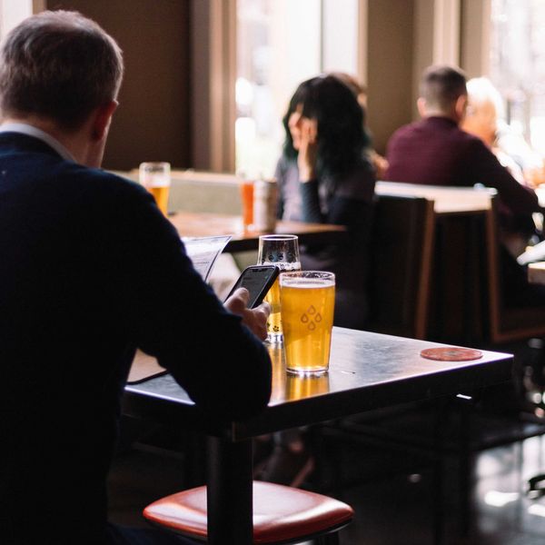 a man sitting at a table with a pint glass of beer.