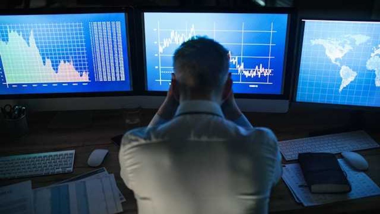 A man sitting in front of computer screens with data charts and maps on the screens