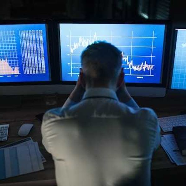A man sitting in front of computer screens with data charts and maps on the screens