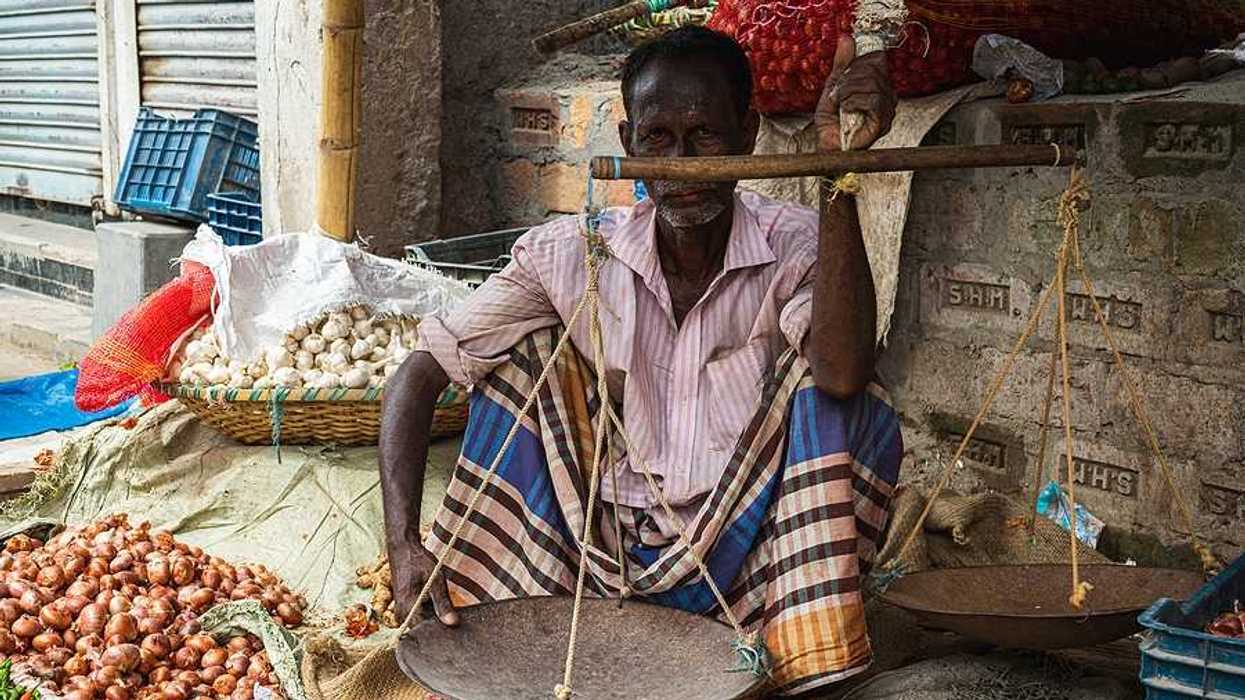 A man sitting on the sidewalk selling onions