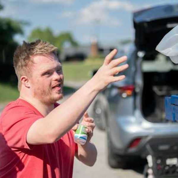 A man throwing a plastic bottle into a recycling bin