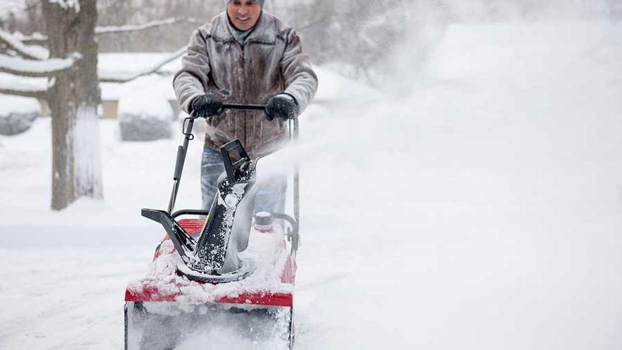 A man using a snow blower on a snowy day