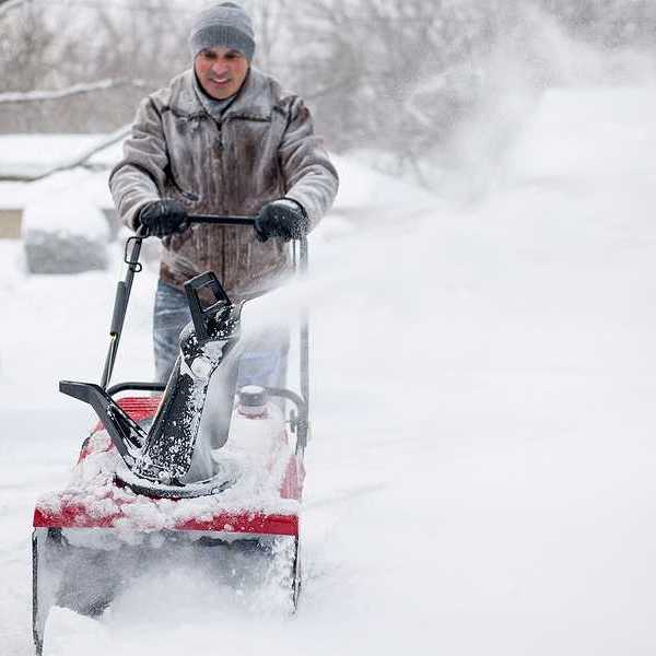A man using a snow blower on a snowy day