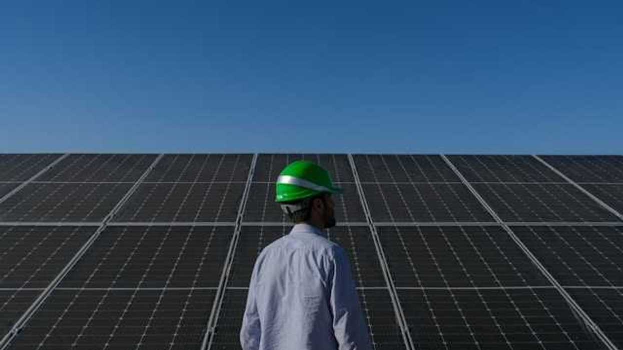 A man wearing a hard hat standing in front of solar panels