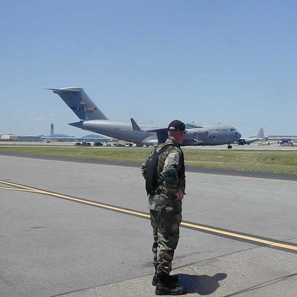 A man wearing camo standing on the tarmac in front of an Air Force plane