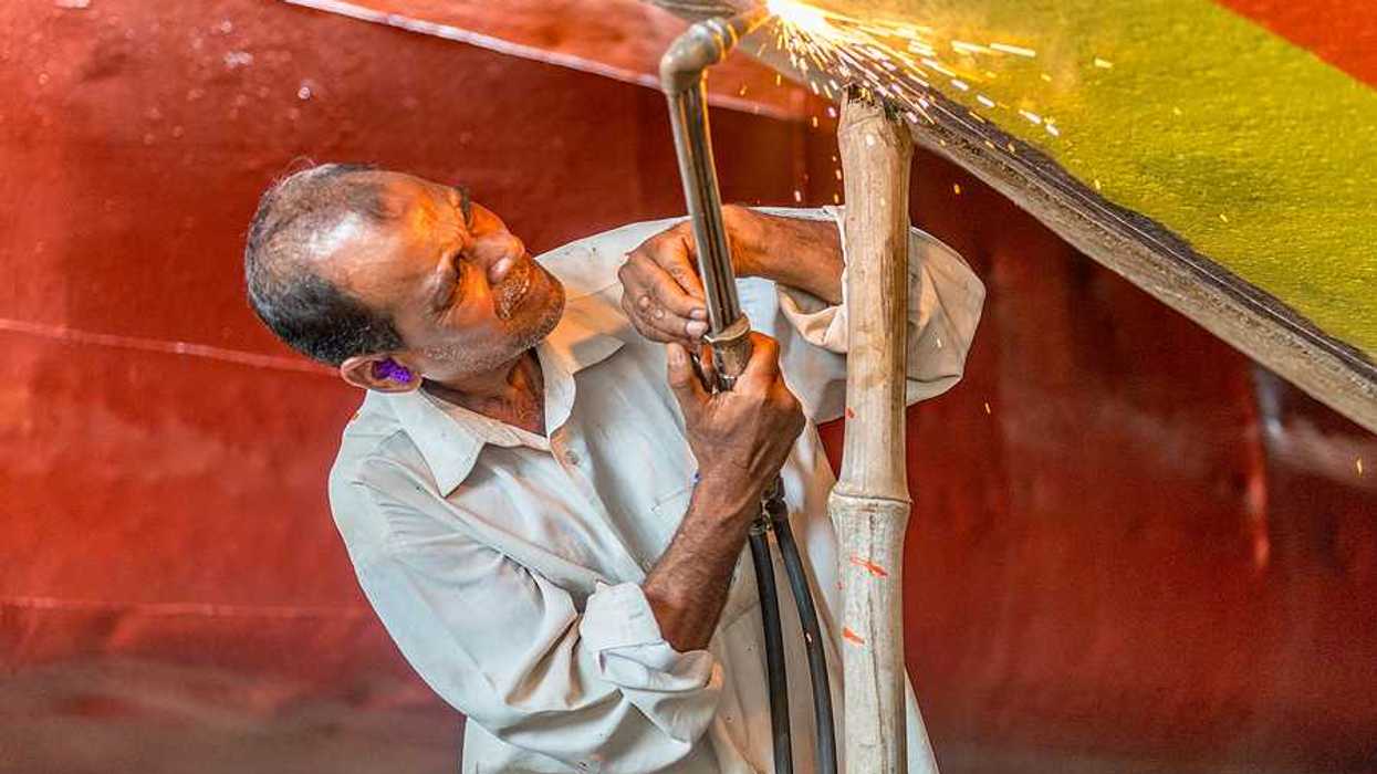 A man welding a piece of metal onto a boat