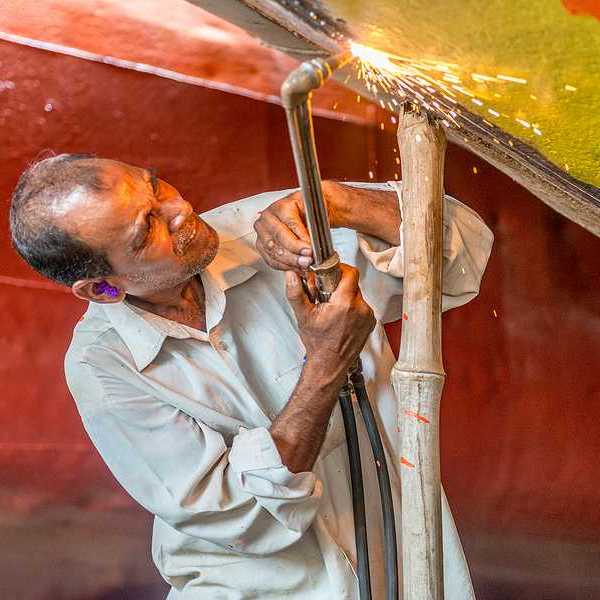 A man welding a piece of metal onto a boat