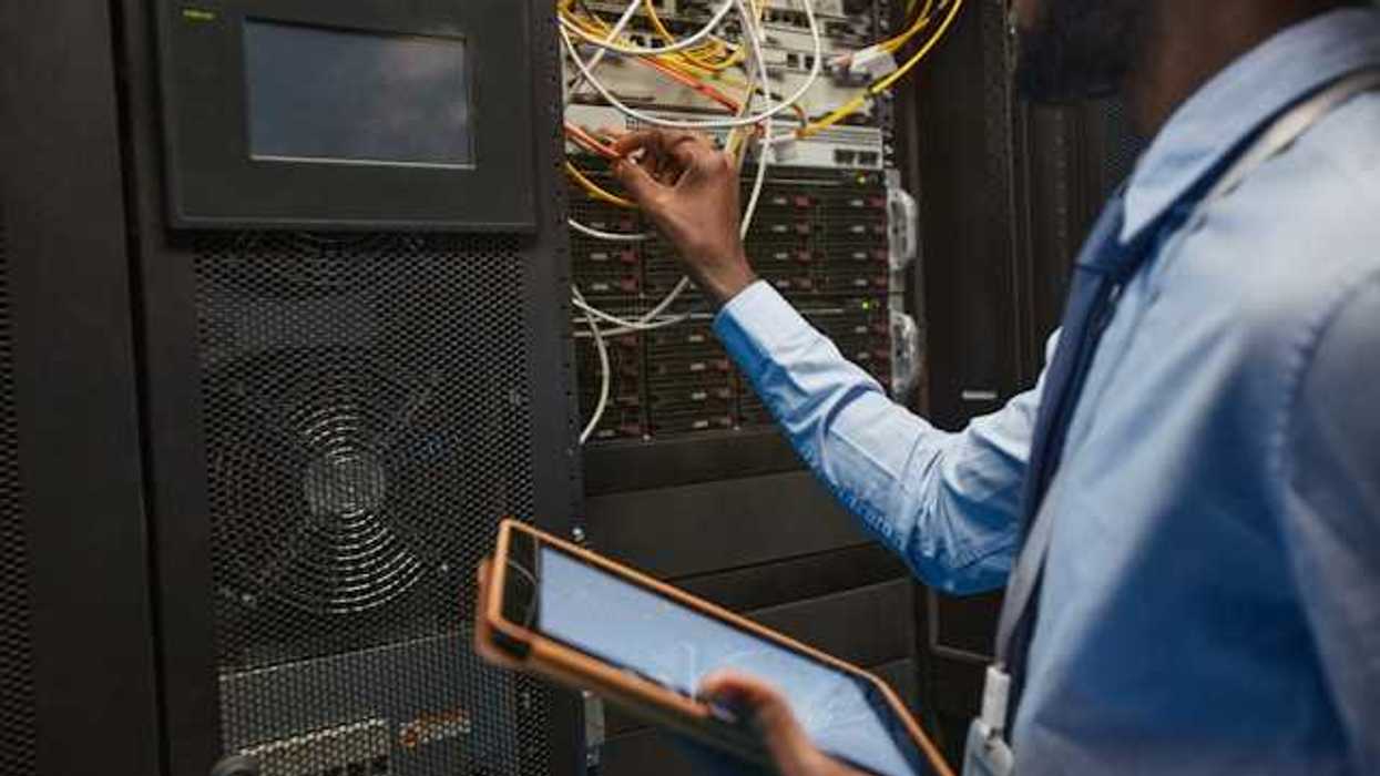 A man working on wires coming out of a server