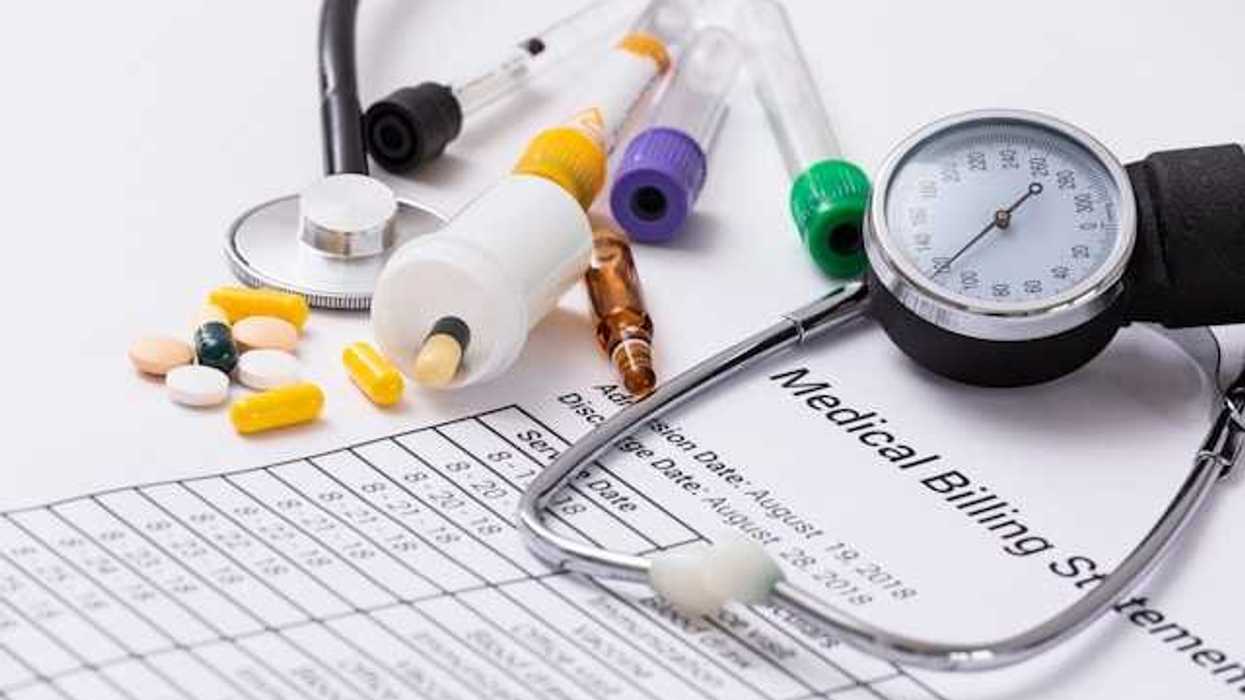 A medical billing statement with a stethoscope and assorted prescription pills next to it