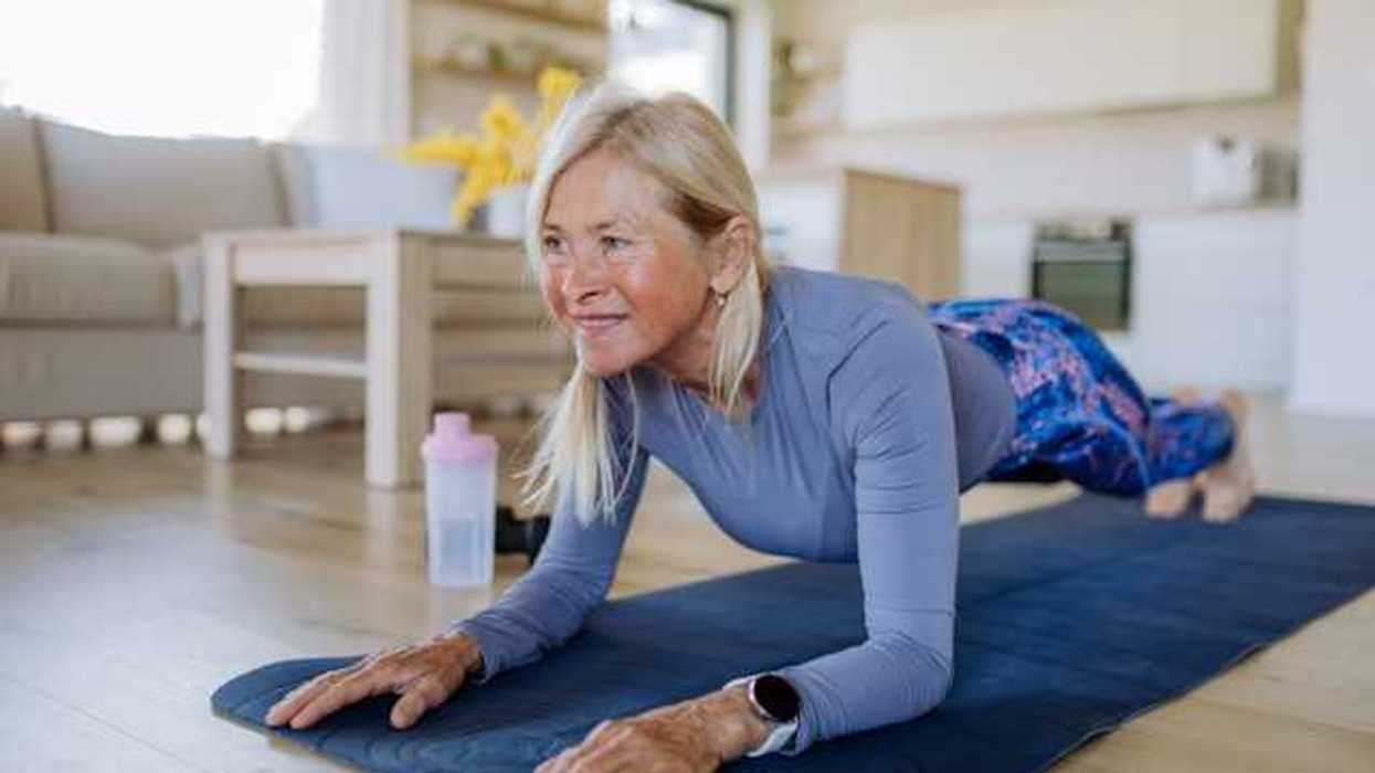 A middle-aged woman doing a plank on a blue yoga mat