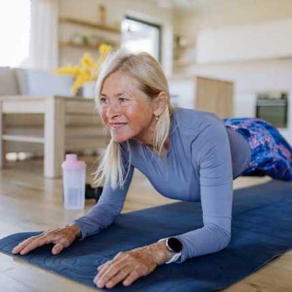 A middle-aged woman doing a plank on a blue yoga mat