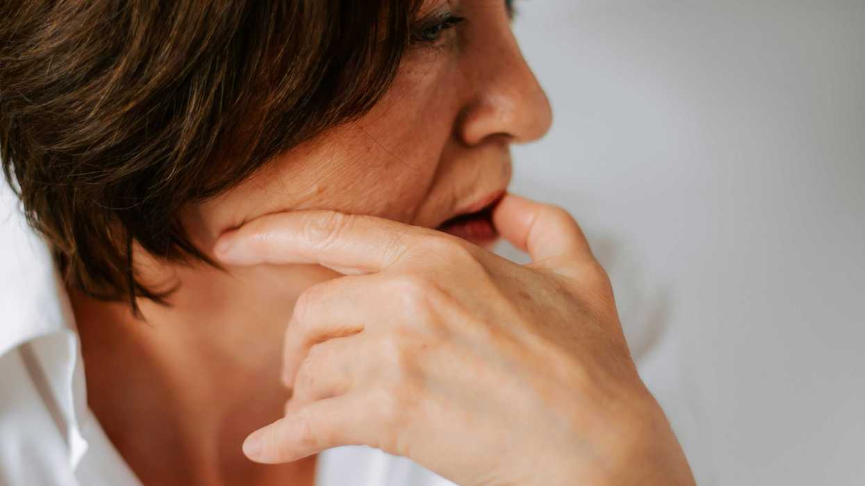 a middle-aged woman with her hand on her chin.