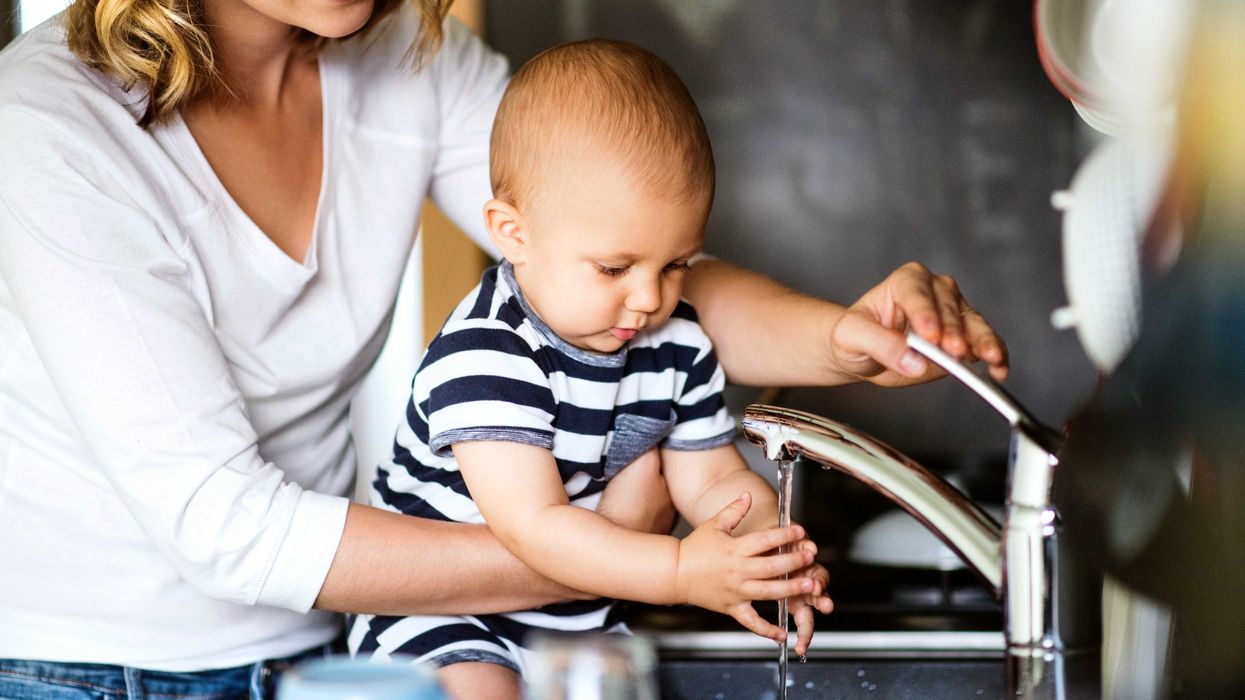 A mother and a child wash their hands in the sink