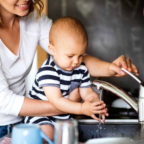 A mother and a child wash their hands in the sink