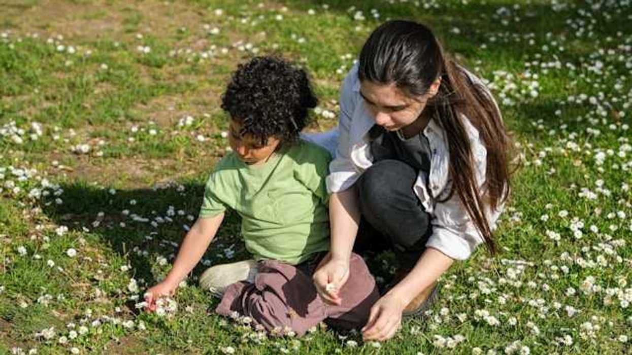 A mother and her son picking wildflowers in a field