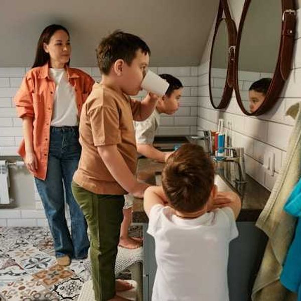 A mother watching her children brush their teeth