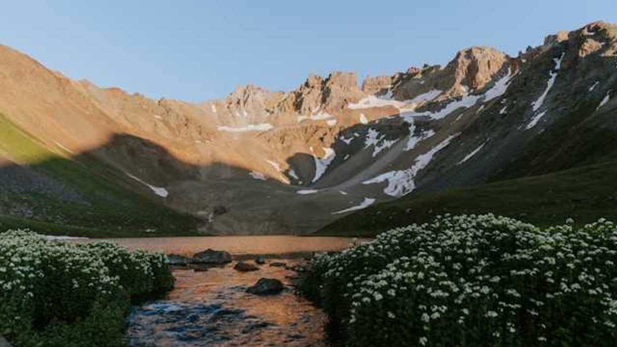 A mountain range with light snow above a lake