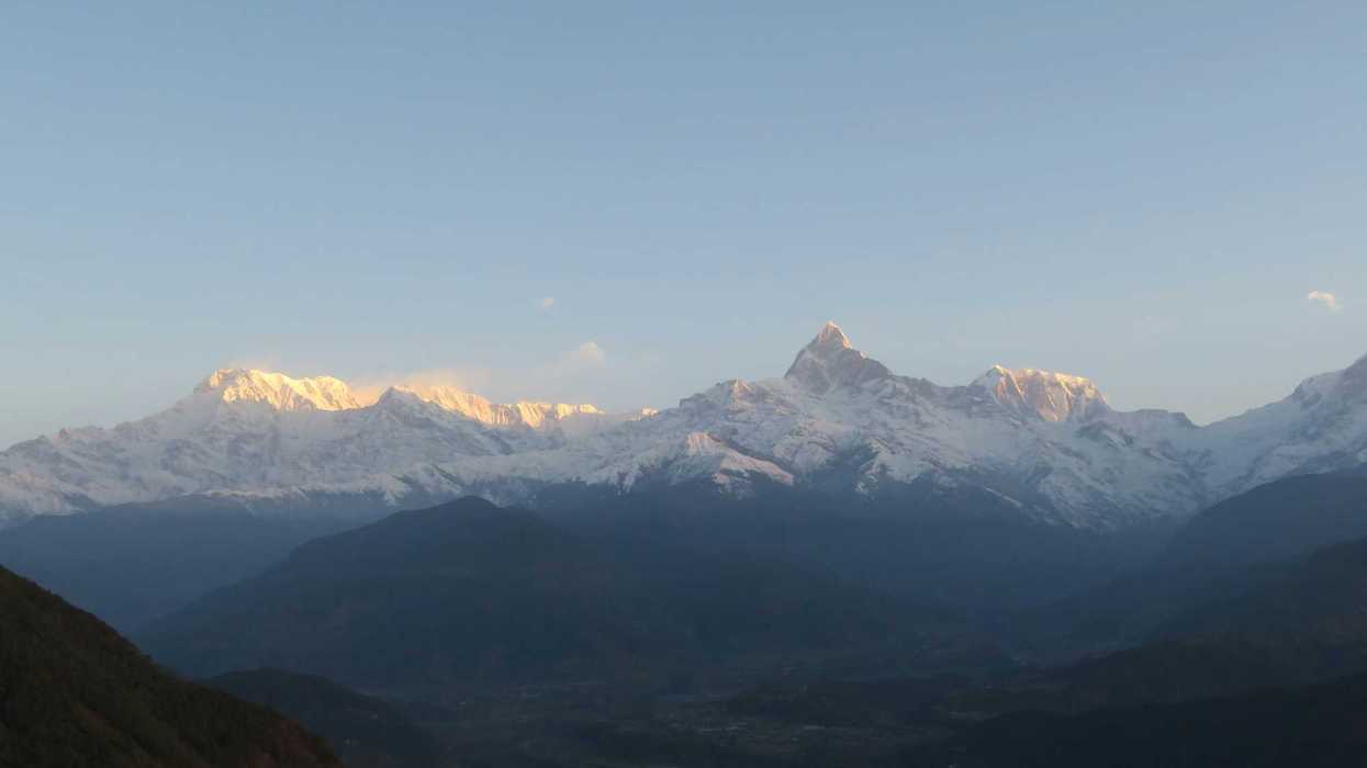 a mountain range with snow capped mountains in the distance.