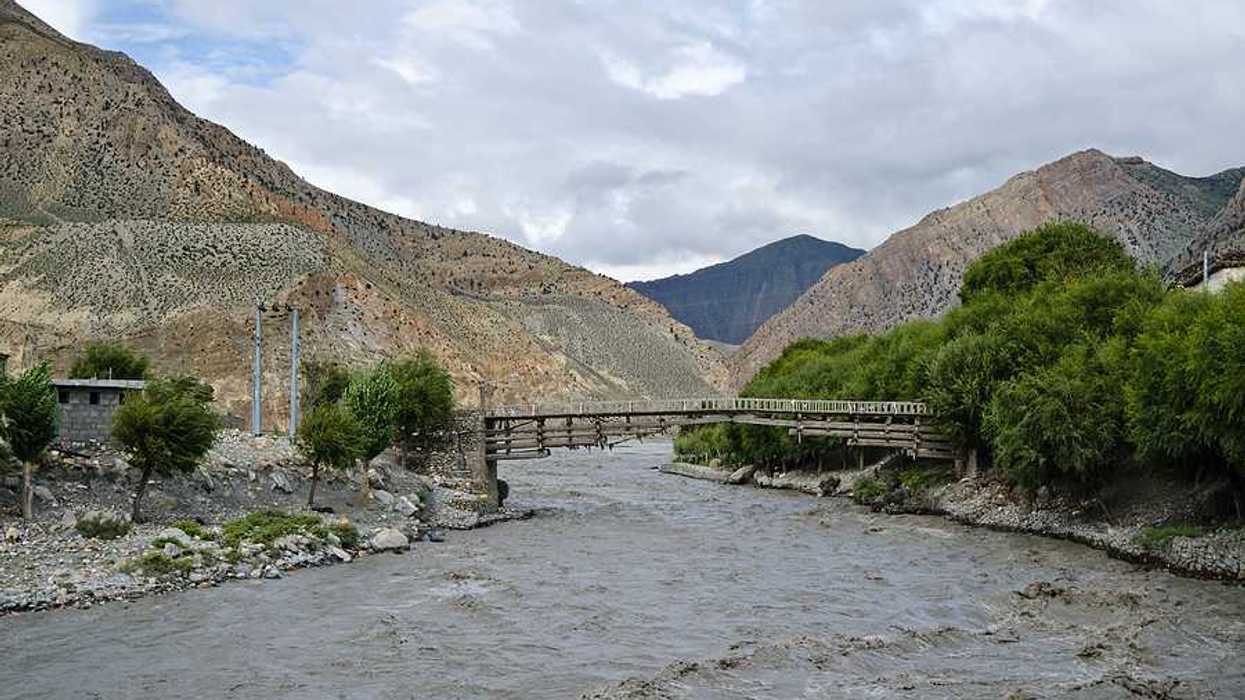 A muddy rising river in a valley in Nepal