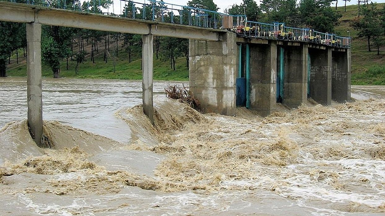 A narrow concrete bridge with fast flood waters streaming below it.