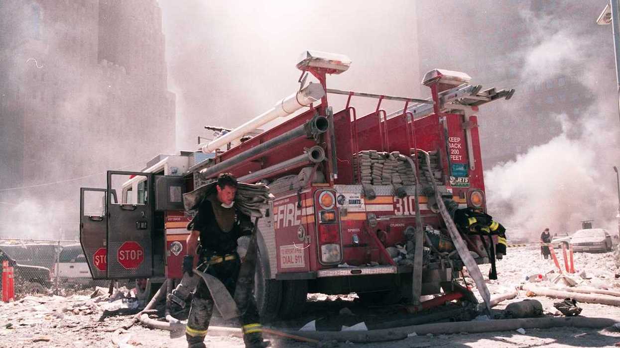 A New York City firefighter carries a fire hose as he works near the area known as Ground Zero after the collapse of the Twin Towers September 11, 2001 in New York City.