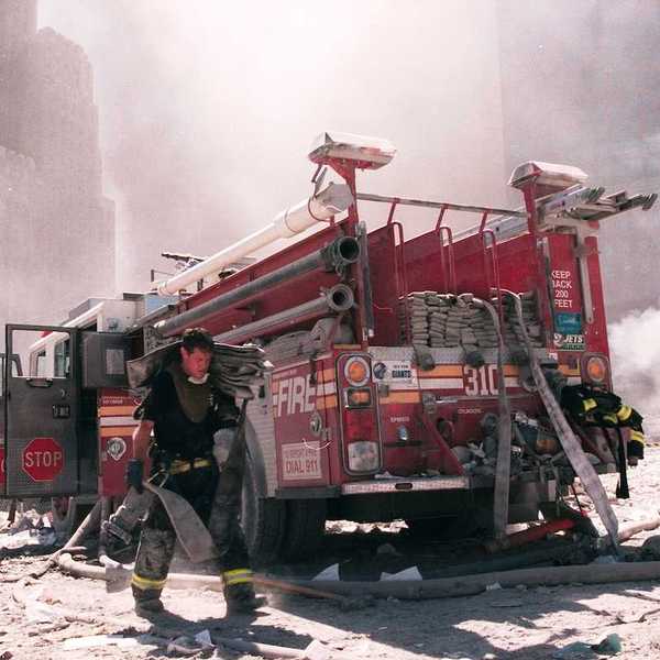A New York City firefighter carries a fire hose as he works near the area known as Ground Zero after the collapse of the Twin Towers September 11, 2001 in New York City.