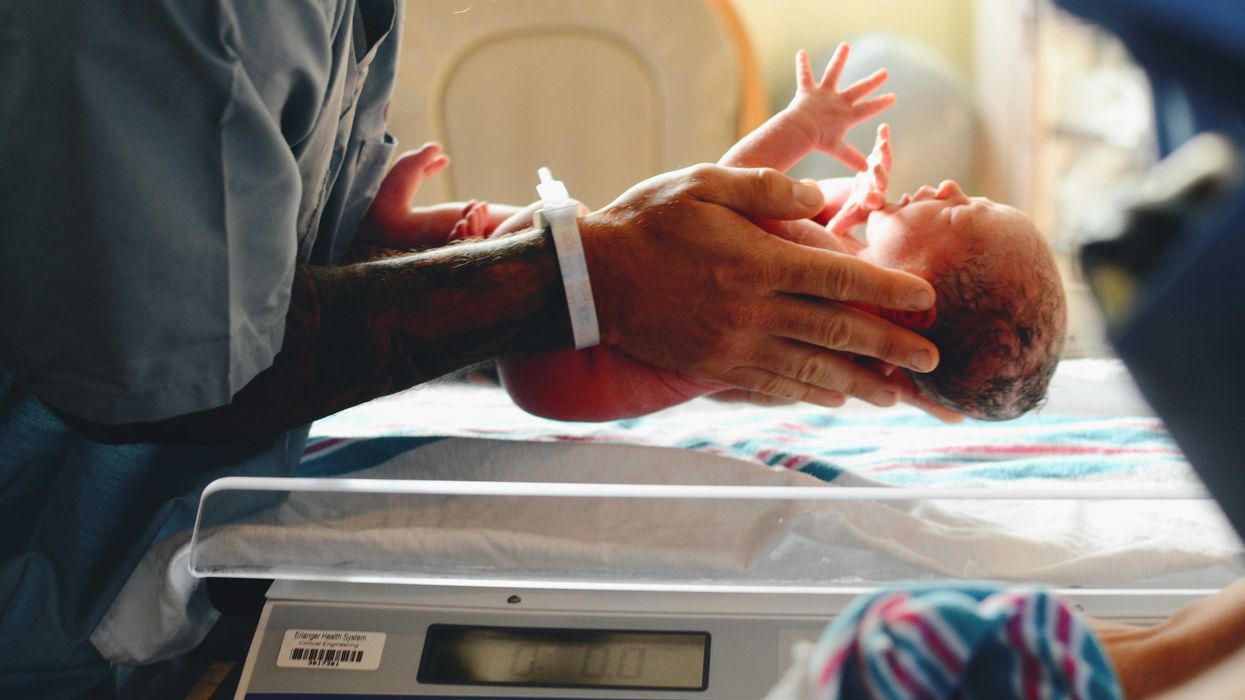 A newborn infant is weighed on a scale